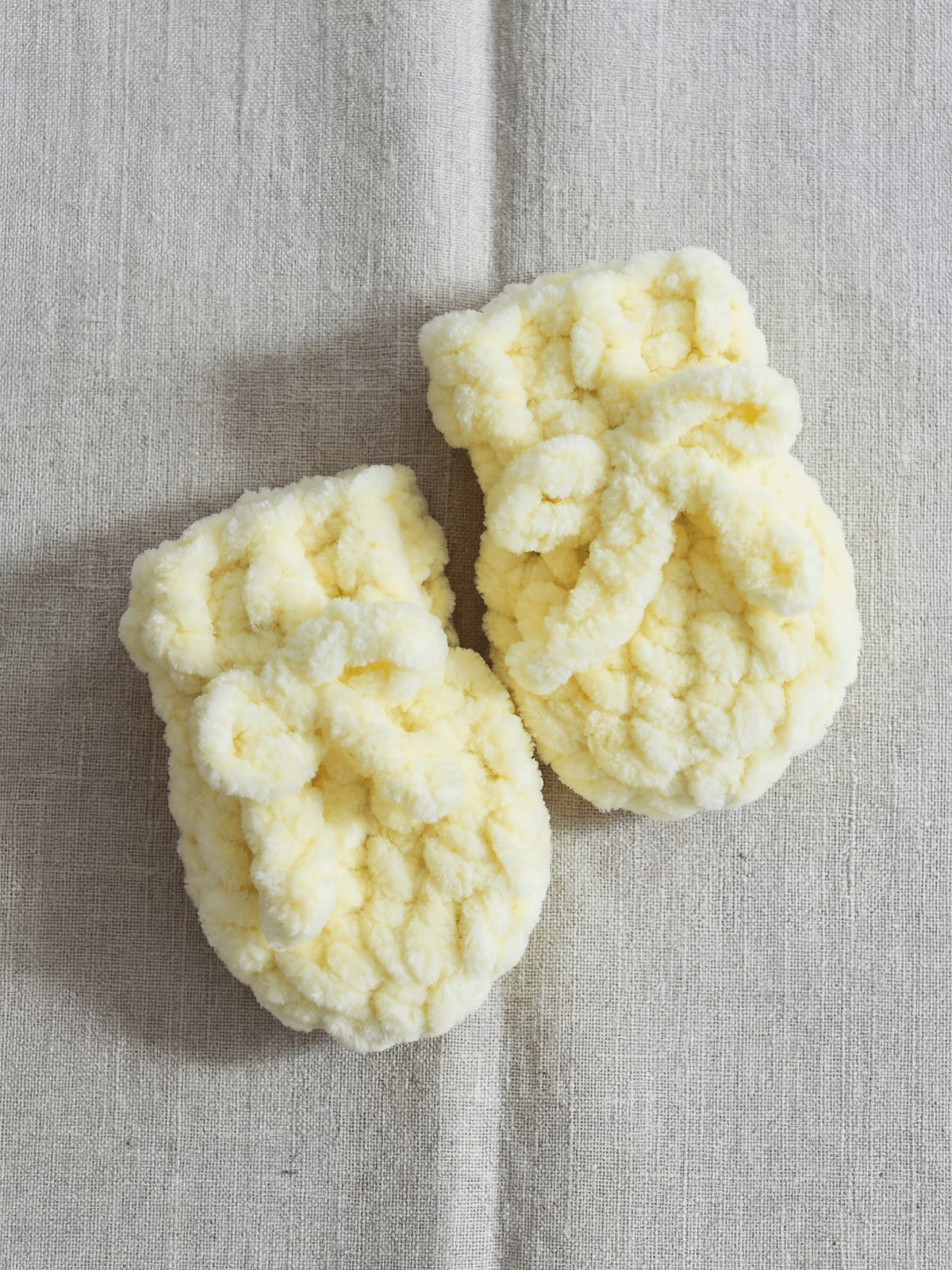 close up of fast crochet baby mittens made with yellow chunky plush yarn